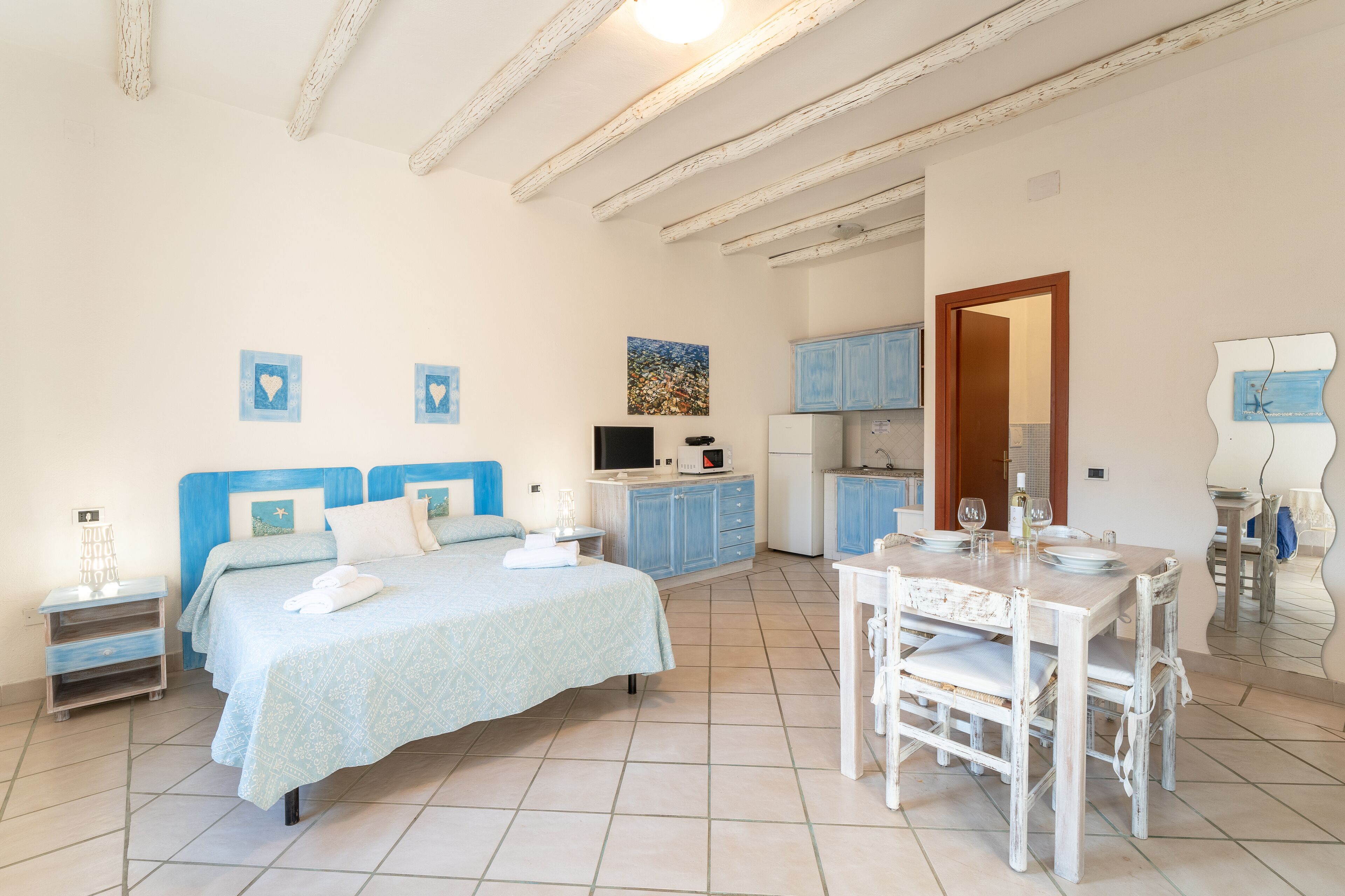 Een slaapkamer met een bed, nachtkastjes, een bureau en een kitchenette.