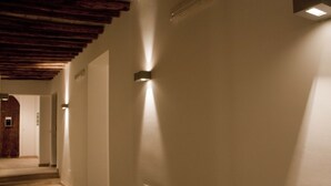 Un pasillo con vigas de madera en el techo, paredes blancas e iluminación empotrada.