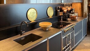 A modern kitchen with dark cabinetry, a stainless steel sink, and a large stove.