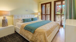 Un dormitorio con cama, mesitas de noche, lámpara y vistas al exterior a través de una puerta.