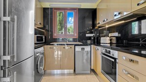 Una cocina moderna con electrodomésticos de acero inoxidable, lavavajillas y ventana con vistas a la vegetación.