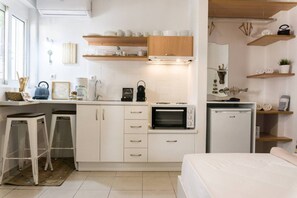 Een kleine keuken met witte kastjes, een ingebouwde magnetron en een koffieapparaat.