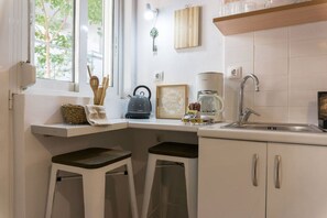 A compact kitchen with a sink, kettle, and a coffee maker on the countertop. - Urban Beach Sand (1Y) (Rethymno)
