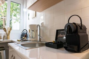 A kitchen with a coffee maker, a kettle, and a black espresso machine. - Urban Beach Sand (1Y) (Rethymno)