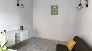 En moderne stue med et hvidt konsolbord, en mørkebrun sofa med gule puder, en hvid stol og en dekorativ vægplakat.
