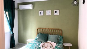 Et soveværelse med en seng, to sengeborde, en fletkurv med håndklæder og en aircondition på væggen.