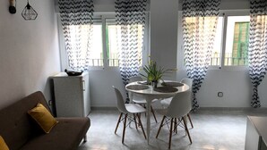 En kompakt bolig med spiseplads, sofa og et lille køkken.