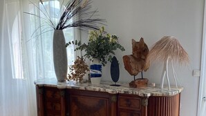 Un mueble de madera con cajones, un jarrón con plantas secas y un adorno encima.