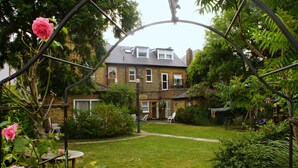 A garden with a patio, a brick house, and a lawn. - Large sunny fresh two bedroom apt in London ideal for tourists, refurbished  (London)
