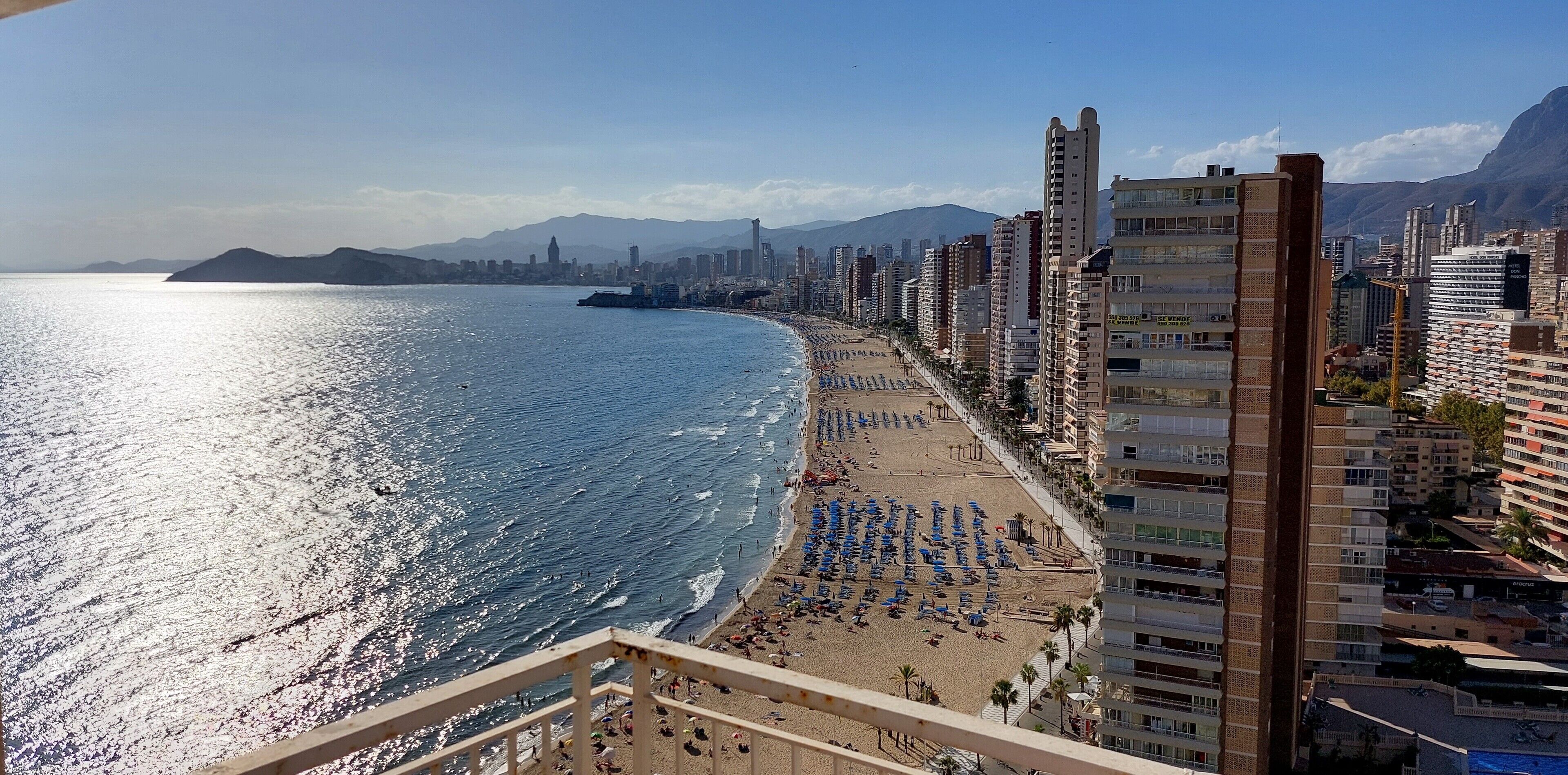A coastal cityscape with a beach, high-rise buildings, and a clear sky.