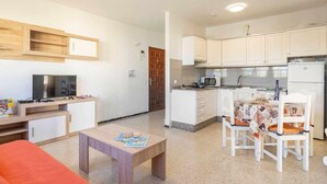 Un espacio habitable compacto con kitchenette, comedor y televisor en la sala.