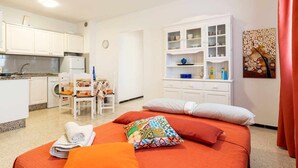 Habitación de hotel con cama, una mesa de comedor con sillas, una zona de cocina y un armario con puertas de vidrio.