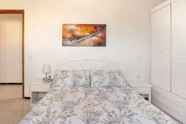 A bedroom with a bed, nightstands, a lamp, and a wardrobe.