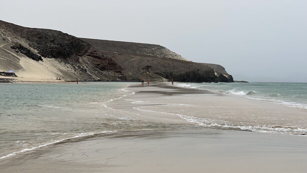 Una playa con un acantilado rocoso y una vista despejada del océano.