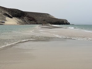 A beach with a rocky cliff and a clear view of the ocean. - Fragata - Centro de Corralejo, playas, restaurantes y ambiente (Corralejo)