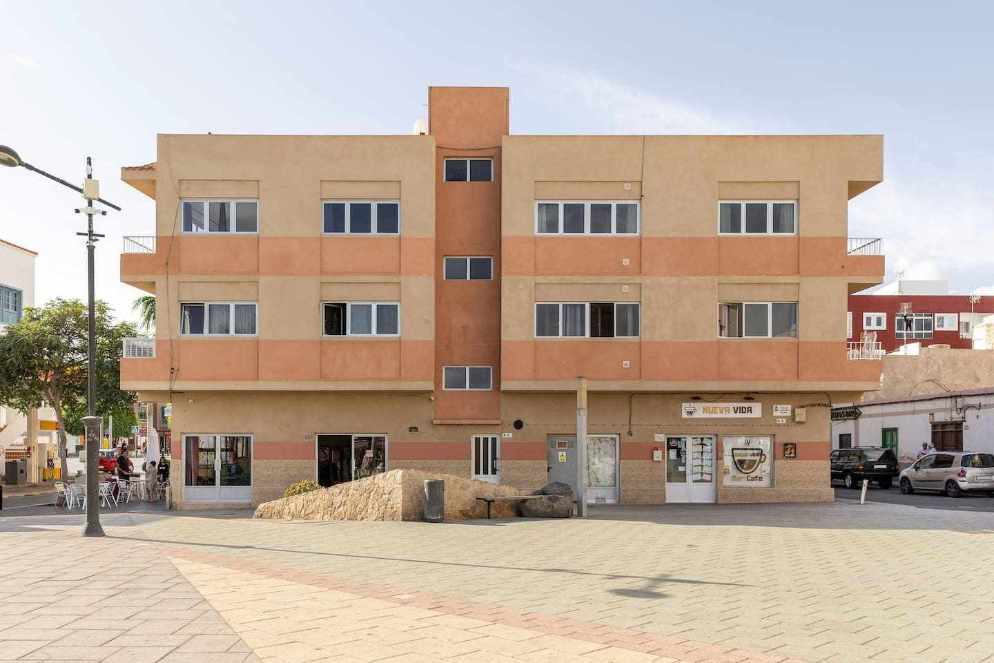 Un edifici de diversos pisos amb façana plana, diverses finestres i entrada a nivell del carrer.