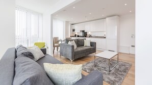 Una sala moderna con un sofá gris, una mesa de centro y un comedor con una silla amarilla.