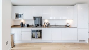 Una cocina moderna con armarios blancos, microondas, hervidor y tostadora.