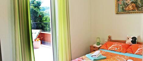 Un dormitorio con cama, un cuadro en la pared y vistas al exterior con vegetación.