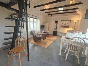A spacious living area with a staircase, a sofa, a coffee table, and a dining set. - Charming cottage on a farm (Ystad V)