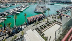 A marina with numerous boats docked, a clear sky, and buildings in the background. - Penthouse Triplex Marina | T2 HsRentals Vilamarina (Vilamoura)