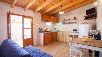 Una cocina compacta con armarios de madera, una mesa de comedor y un sofá en un ambiente acogedor.