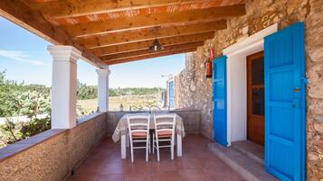 Un patio cubierto con una mesa y sillas, un muro de piedra y una puerta azul.