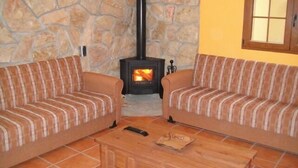 A cozy living room with two striped sofas, a fireplace, and a stone wall.