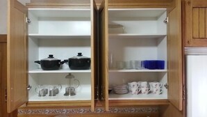 A kitchen with open cabinets displaying kitchenware and utensils.