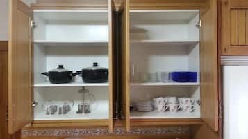 Una cocina con armarios abiertos que exhiben utensilios y vajilla.