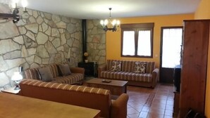 A living room with a stone wall, a sofa, a coffee table, and a dining table.