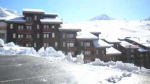 A hotel with multiple buildings, each with balconies and snow-covered roofs, set against a snowy mountainous backdrop. - Vacations in Belle Plagne at the foot of the slopes (Saturday to Saturday rentals) (Belle-Plagne)