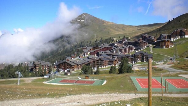 A mountain village with traditional wooden buildings, a tennis court, and a ski lift. - Vacations in Belle Plagne at the foot of the slopes (Saturday to Saturday rentals) (Belle-Plagne)