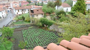 A residential area with terraced houses, a garden with rows of plants, and a road with a traffic sign. - Casa para 5 en el centro de Colombres (Colombres)