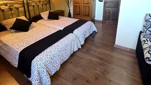 A bedroom with a bed, bedside tables, a wooden wardrobe, a wall-mounted light, and a fire extinguisher. - Casa para 5 en el centro de Colombres (Colombres)