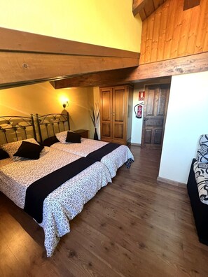Une chambre à coucher comprenant un lit, des tables de chevet, une armoire en bois, un luminaire fixé au mur et un extincteur.