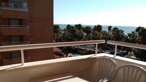 Un balcón con una mesa y sillas, con vistas a un edificio y al mar.