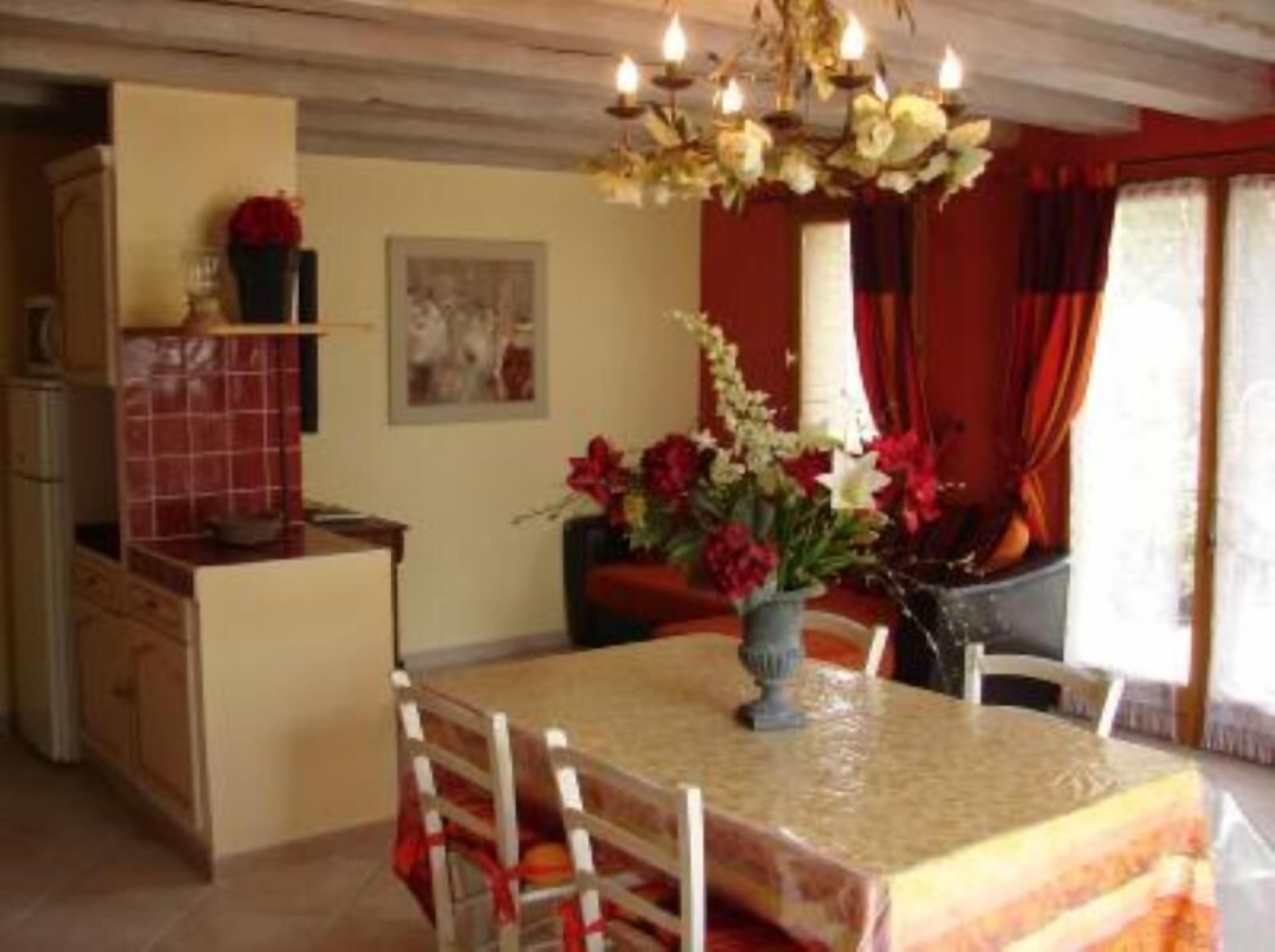 A dining area with a table set for two, a chandelier, and a vase of flowers.