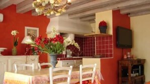 Un comedor con una mesa dispuesta para cuatro personas, rodeada de sillas blancas.