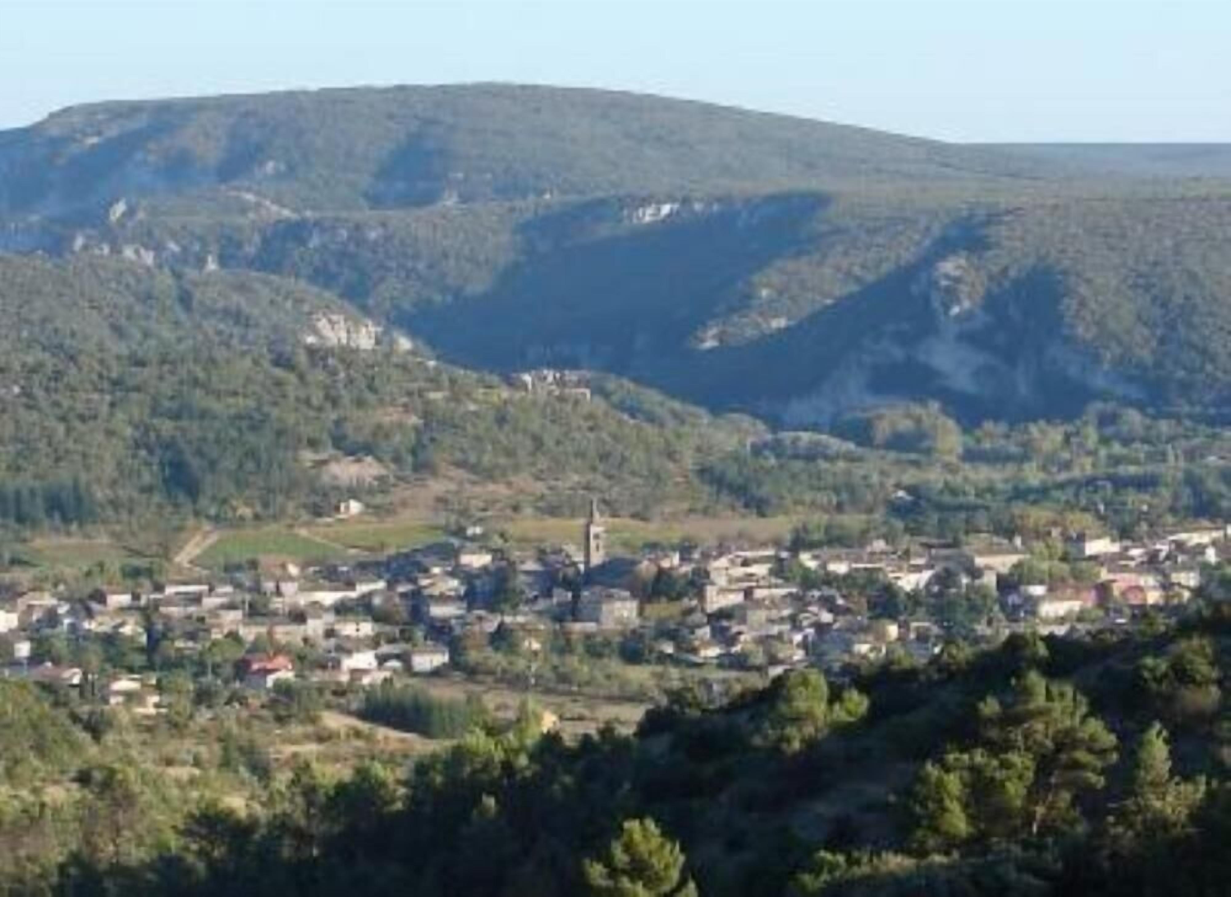 A town nestled in a valley with a prominent hill in the background.