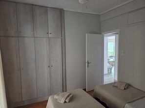 A bedroom with two beds, a wardrobe, and a door leading to a balcony. - Great Terrace and perfect view in Vouliagmeni (Vouliagmeni)
