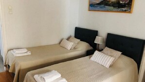 A hotel room with two beds, each with a beige bedspread and pillows, and a painting on the wall. - Great Terrace and perfect view in Vouliagmeni (Vouliagmeni)