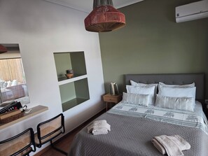 A hotel room with a bed, a desk, a chair, a hanging light fixture, and a window. - Great Terrace and perfect view in Vouliagmeni (Vouliagmeni)