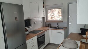A compact kitchen with a built-in refrigerator, oven, and sink. - Great Terrace and perfect view in Vouliagmeni (Vouliagmeni)