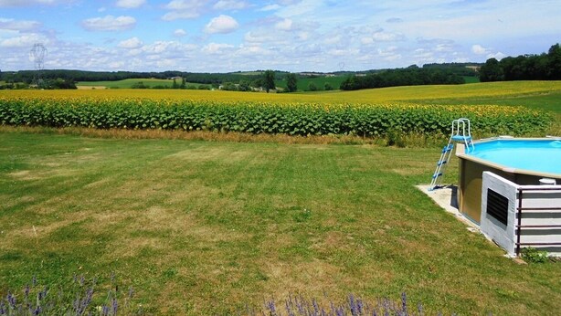 A swimming pool with a ladder, surrounded by a grassy lawn and a field of sunflowers. - Characterful and Spacious 2 Bedroom Gite, Sleeps 4 with Dedicated Pool (Pillac)