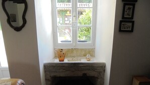 A room with a stone bench under a window, a small table with a vase, and framed pictures on the wall. - Characterful and Spacious 2 Bedroom Gite, Sleeps 4 with Dedicated Pool (Pillac)