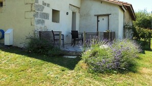 A rustic building with a stone facade, a small porch with outdoor seating, and a garden with lavender. - Characterful and Spacious 2 Bedroom Gite, Sleeps 4 with Dedicated Pool (Pillac)