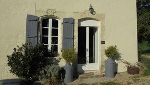 A building with two windows, a door, and a small balcony. There are potted plants in front of the building. - Characterful and Spacious 2 Bedroom Gite, Sleeps 4 with Dedicated Pool (Pillac)