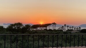 A sunset over a body of water with palm trees and distant mountains. - Villa with pool surrounded by olive groves. With sea view.Casa in campagna.  (Alghero)