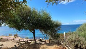 A dirt path leading to a beach with a wooden fence and benches. - Villa with pool surrounded by olive groves. With sea view.Casa in campagna.  (Alghero)